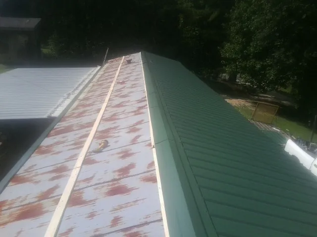 Old rusted panels beside newly installed green metal roofing — Wind Damage Roof Repair by Roofing Brothers in Olathe