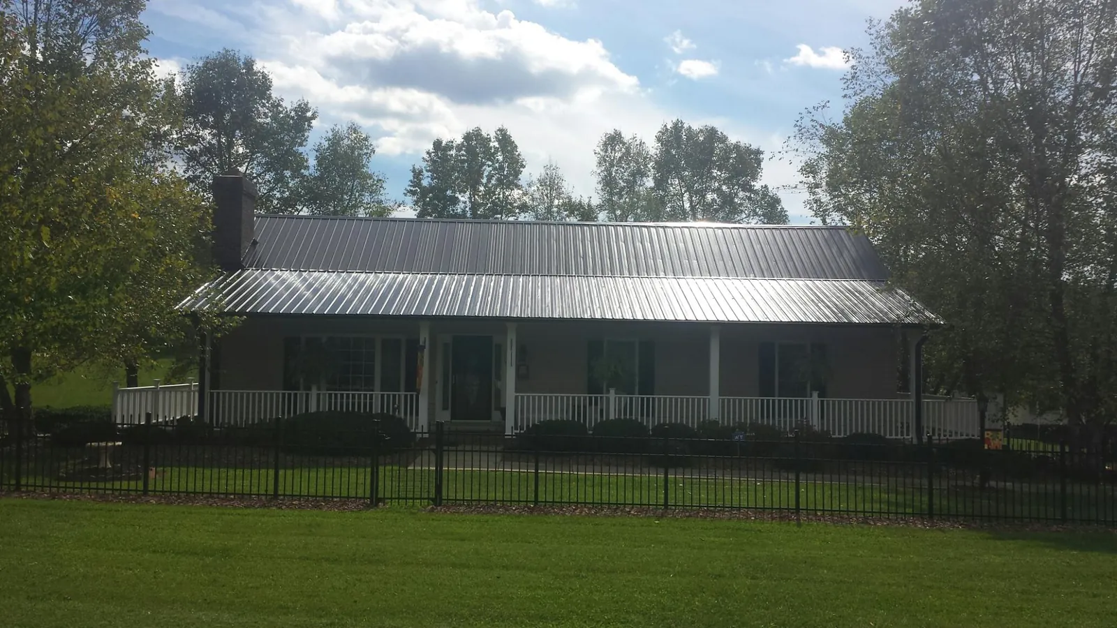 Gray metal roof on a brick ranch with a full width front porch — Gutter Guard Installation work by our crew in Olathe