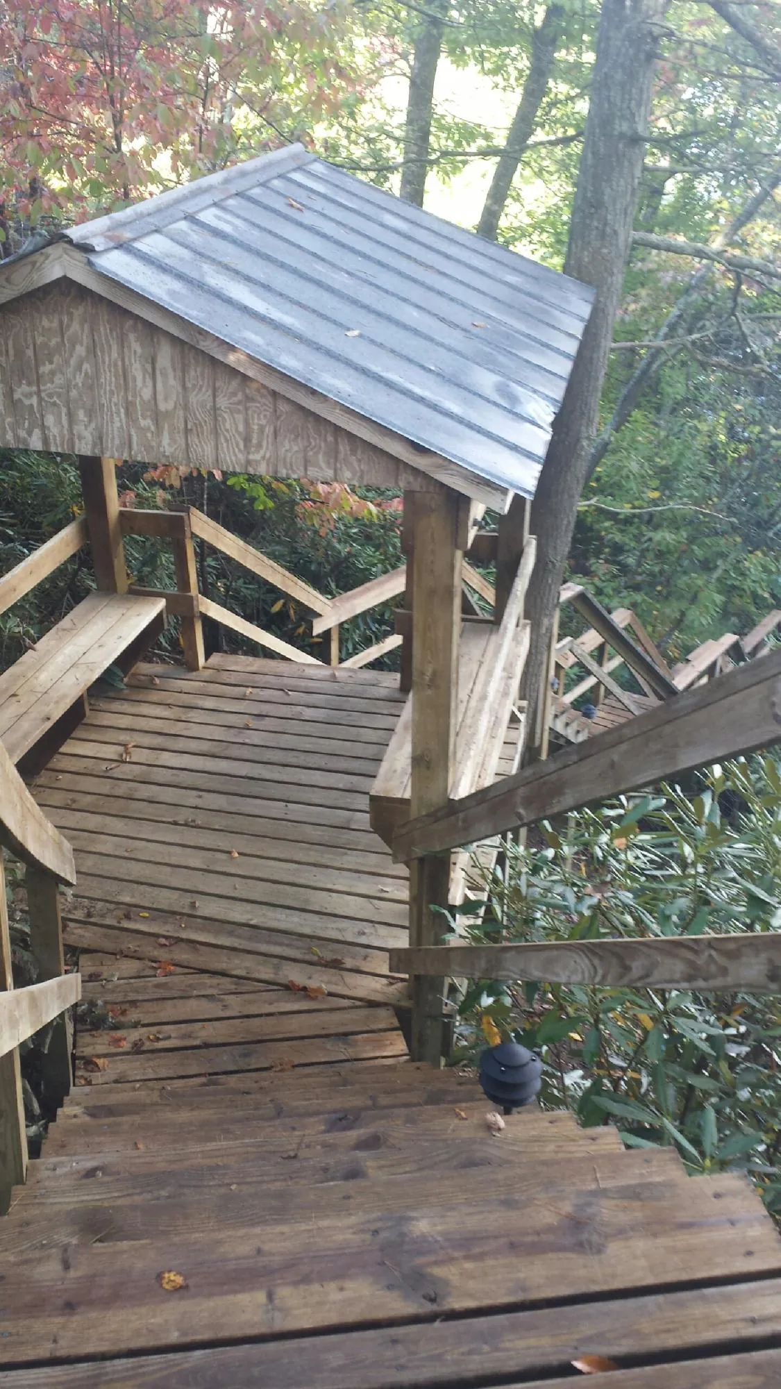 Metal roofed shelter over wooden steps on a wooded walkway — Skylight Repair & Installation work by our crew in Olathe